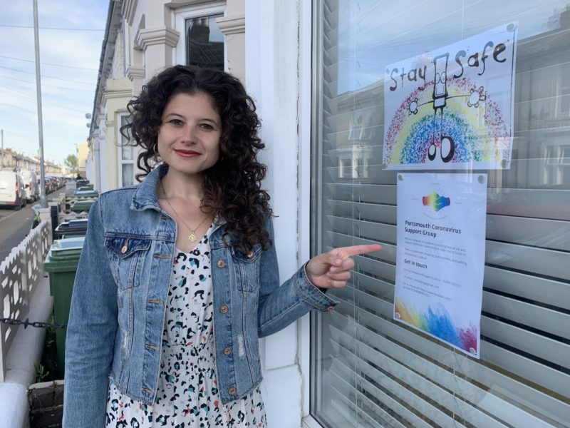 Charlotte proudly displaying a My Dog Sighs and Covid-19 Support Group posters in her window